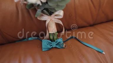 漂亮的结婚花束躺在沙发上，戴着结婚戒指和新郎的领结